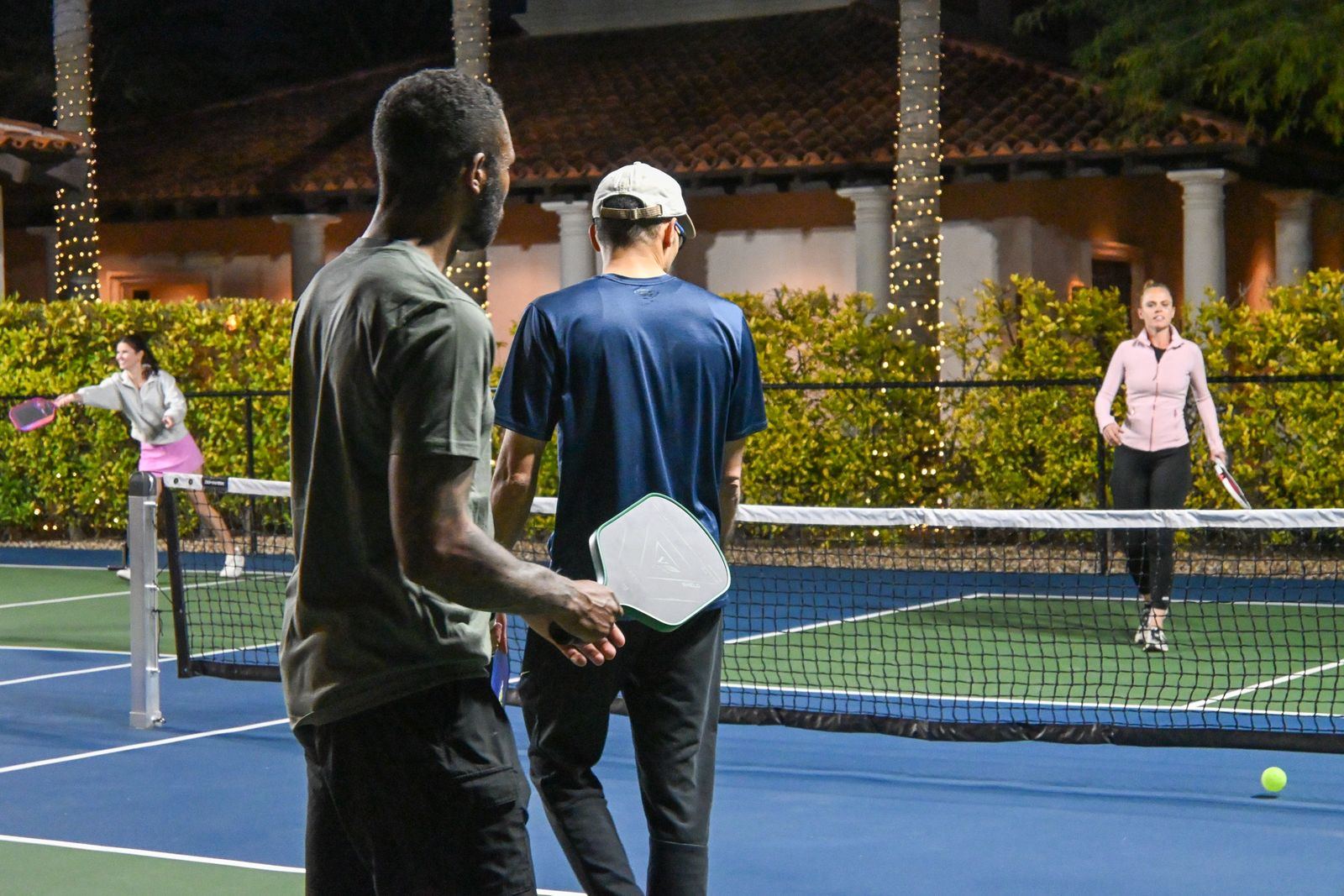 Players watching a doubles rally from behind the baseline